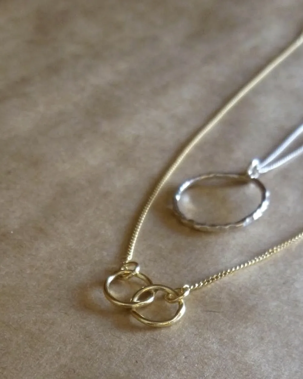 Two circular pendant necklaces arranged on a neutral surface.