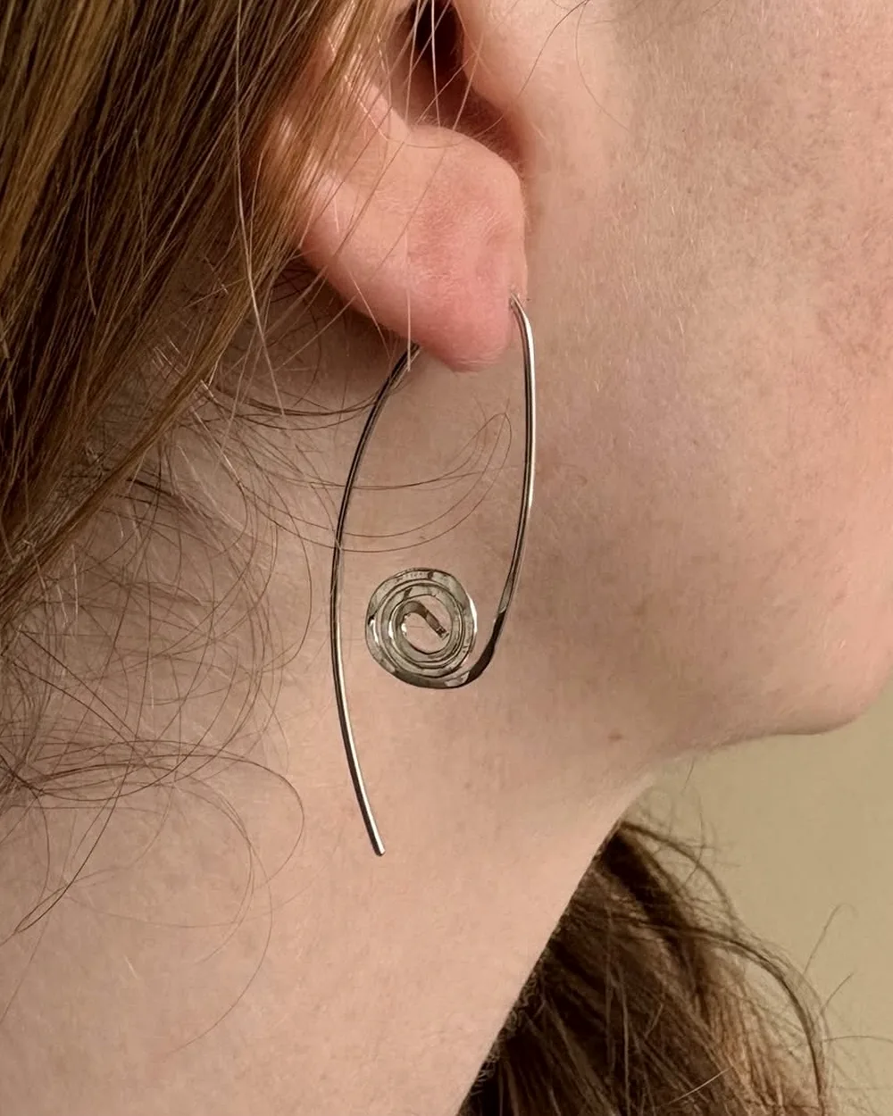 Spiral drop earring worn on the ear, showing its real drop length.