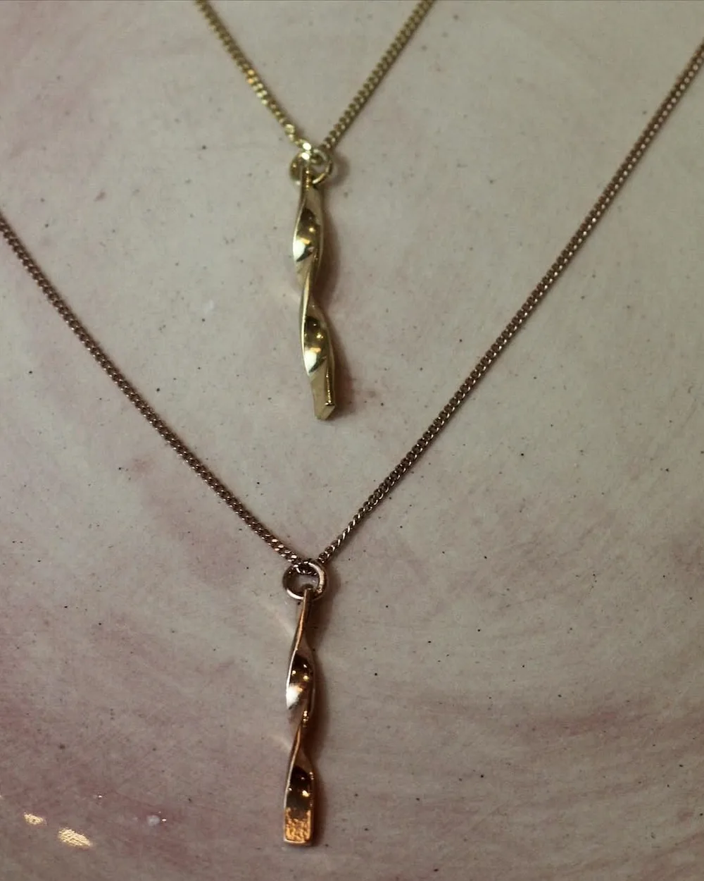 Two twisted drop pendant necklaces worn together for scale.